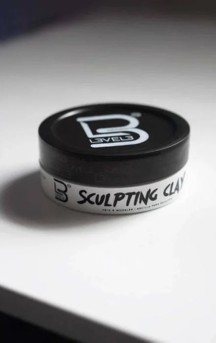 Jar of sculpting clay with a black lid on a white surface